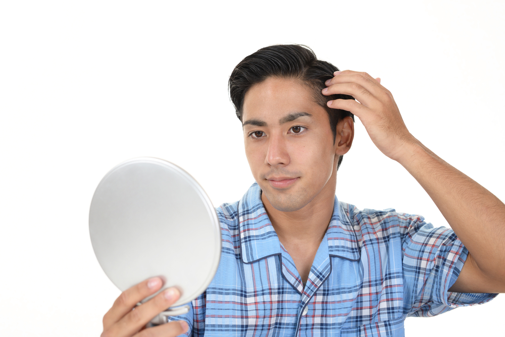 手鏡で頭皮の炎症を確認している男性